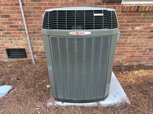 An outdoor heat pump unit beside a brick house